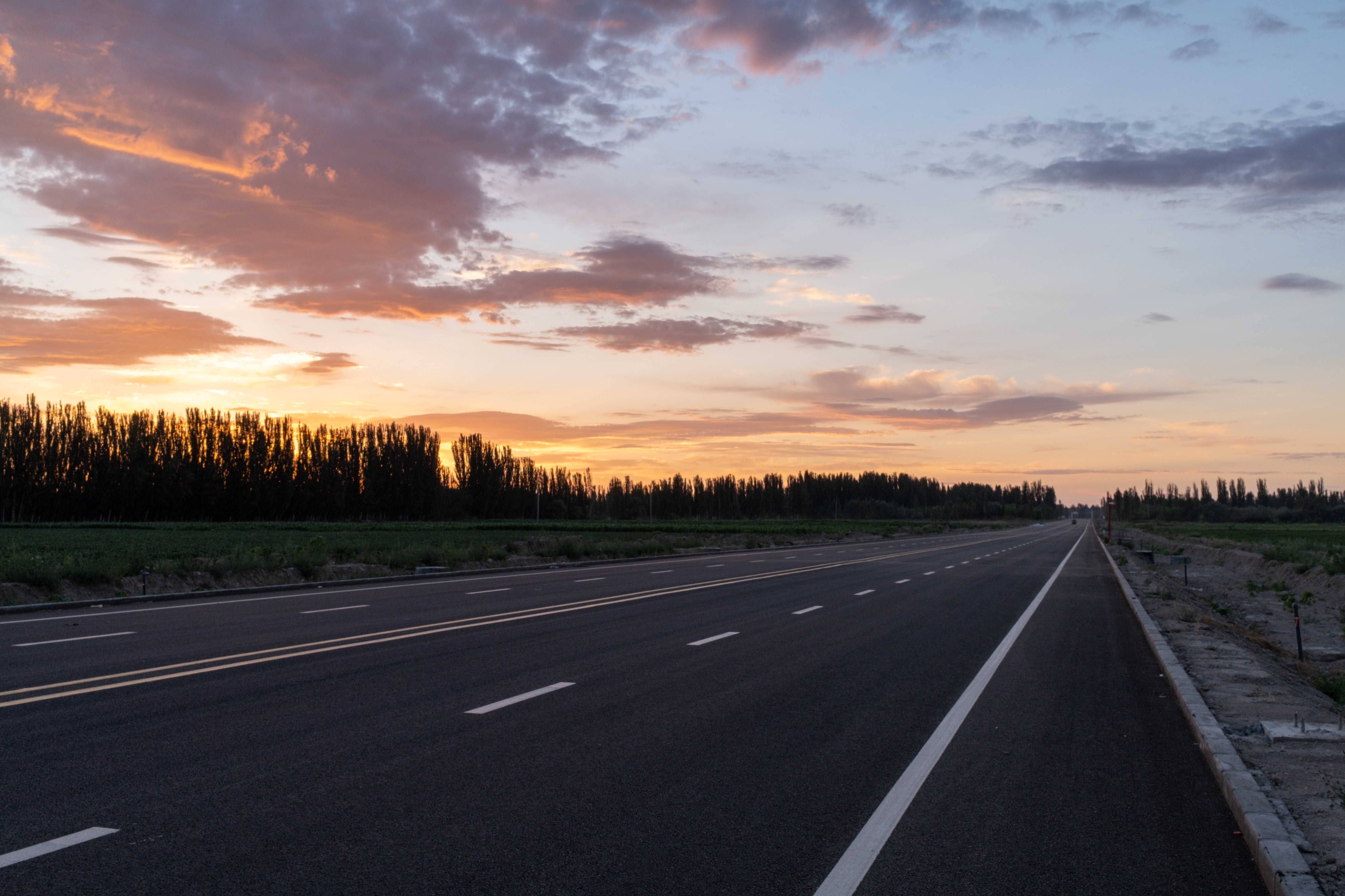 Traversing a Gray Asphalt Road During Sunset