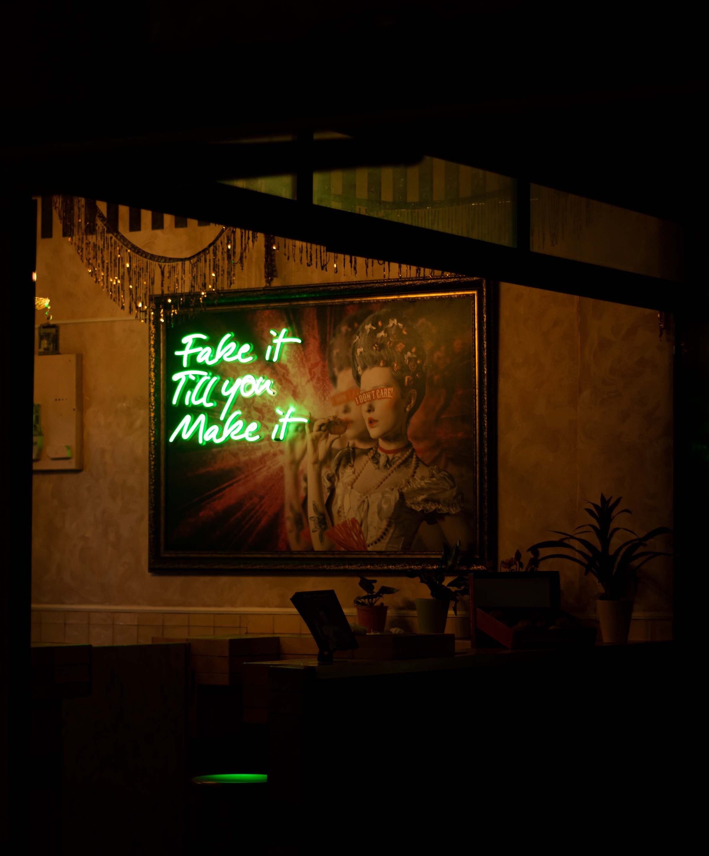 A Green Neon Sign of Fake It Till You Make It on a Painting