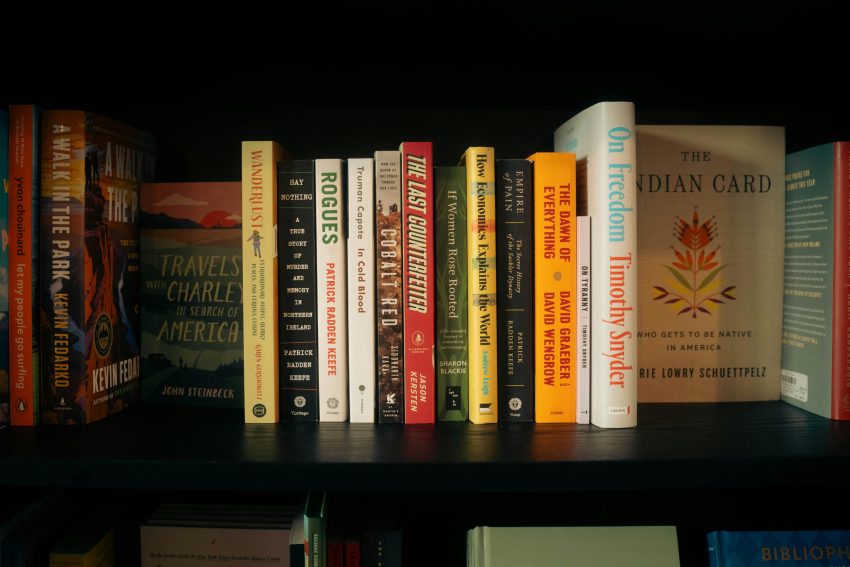 a vertical stack of books on a shelf. title: 5 must read books to add to your reading list