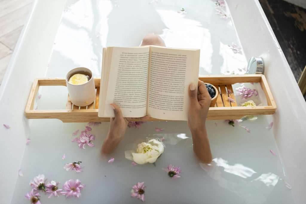 woman reading a book while resting in a bathtub